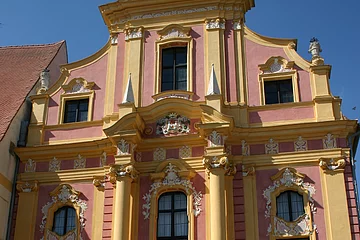 Die Staatliche Provinzialbibliothek von außen fotografiert. Das Gebäude im Frührokokobaustil  mit seiner reichen Fassadengliederung in rosa und gelber Farbe gehalten.