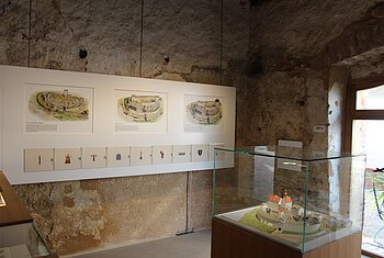 Altmühlzentrum Dollnstein - Burgenraum Ausstellungsraum mit historischen Burgzeichnungen und einem Modell in einer Glasvitrine.