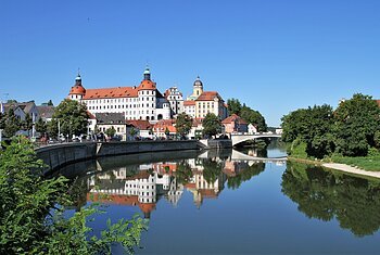 Stadtansicht mit Schloss und Brücke, Spiegelung im Fluss, blauer Himmel, Bäume am Ufer
