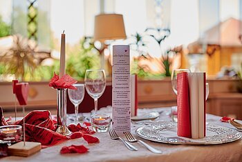 Candle-Light-Dinner im Landhotel "Zur Jurahöhe" Romantisch gedeckter Tisch mit Kerze, Weingläsern und roter Dekoration bei Tageslicht.