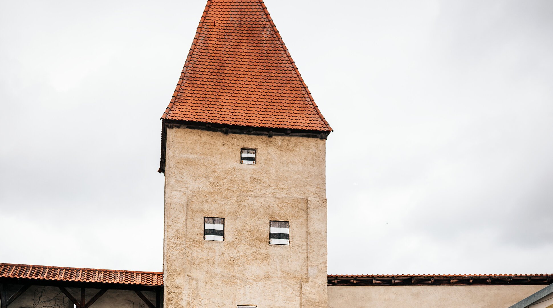 Zwei Radfahrer fahren an einem historischen Stadttor mit rotem Dach und Durchfahrt vorbei.