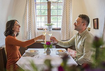 Am gedeckten Tisch in der Gaststube "Zum Klosterbräu" in Bergen im Naturpark Altmühltal Ein Pärchen sitzt am gedeckten Tisch in der gemütlichen Gaststube des Restaurants "Zum Klosterbräu" in Bergen im Naturpark Altmühltal. Die beiden stoßen mit Weißwein an.